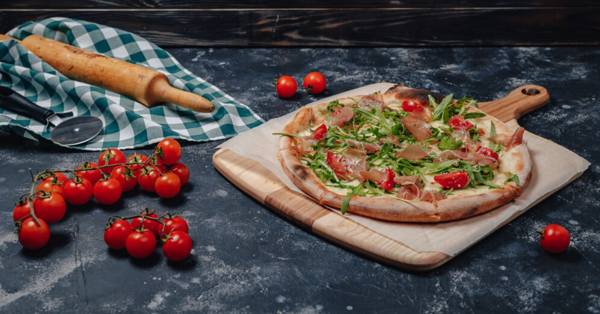 Freshly baked Pomodoro Pizza on rustic wooden table surrounded by ingredients